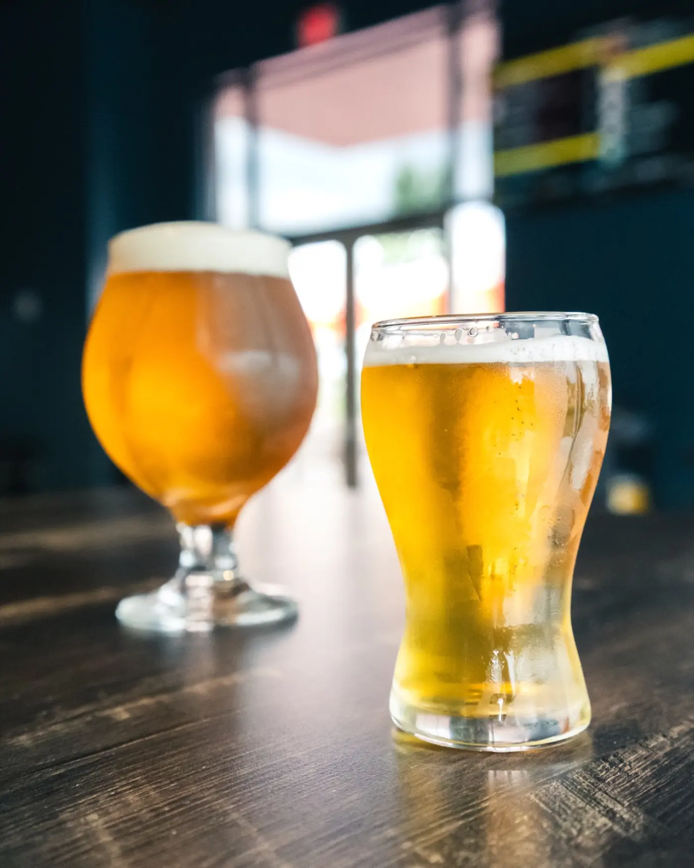 Snifter and pilsner pours on the bar in front of the open taproom entrance