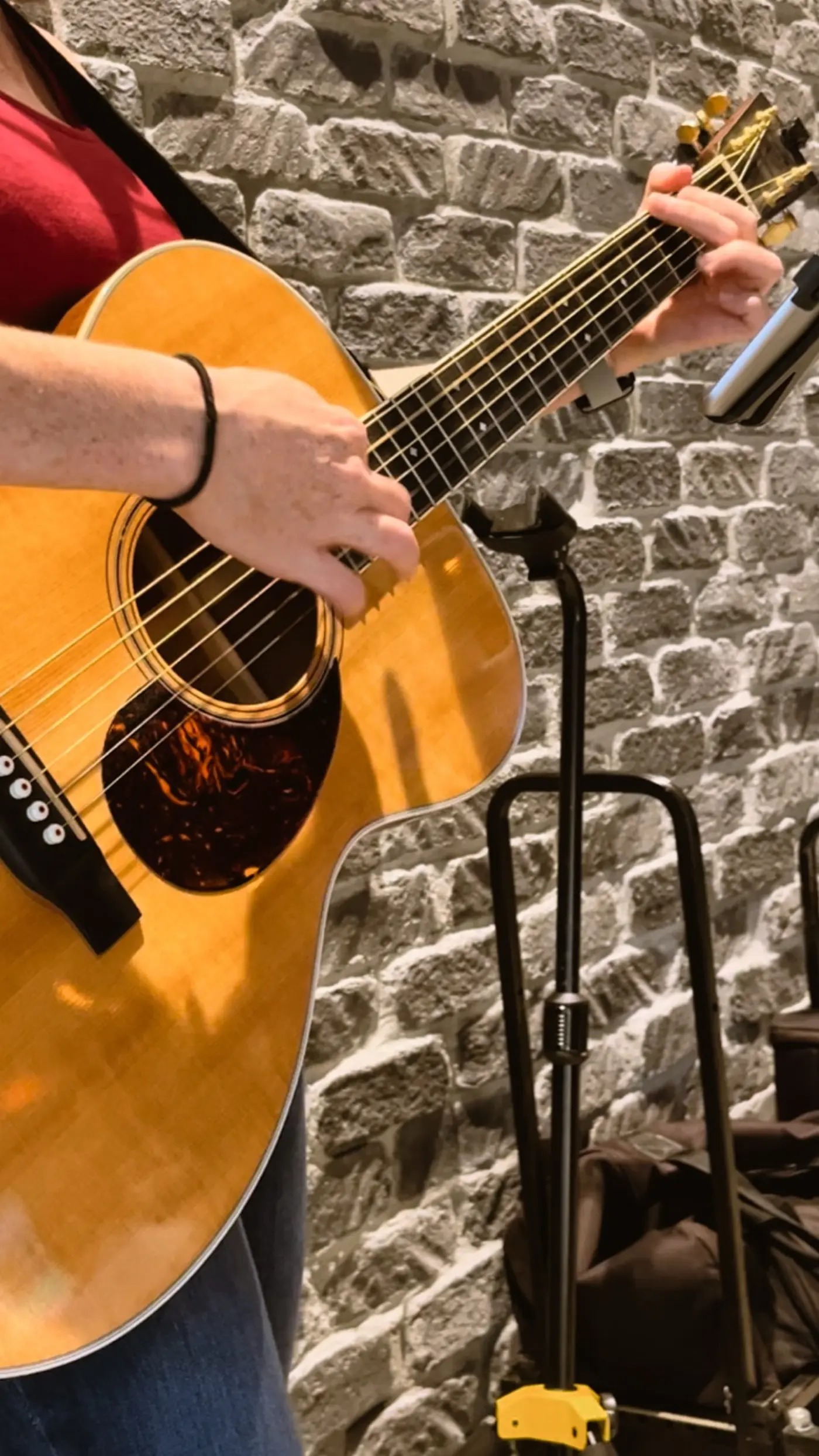Acoustic guitar being played against the taproom's stone feature wall during live music
