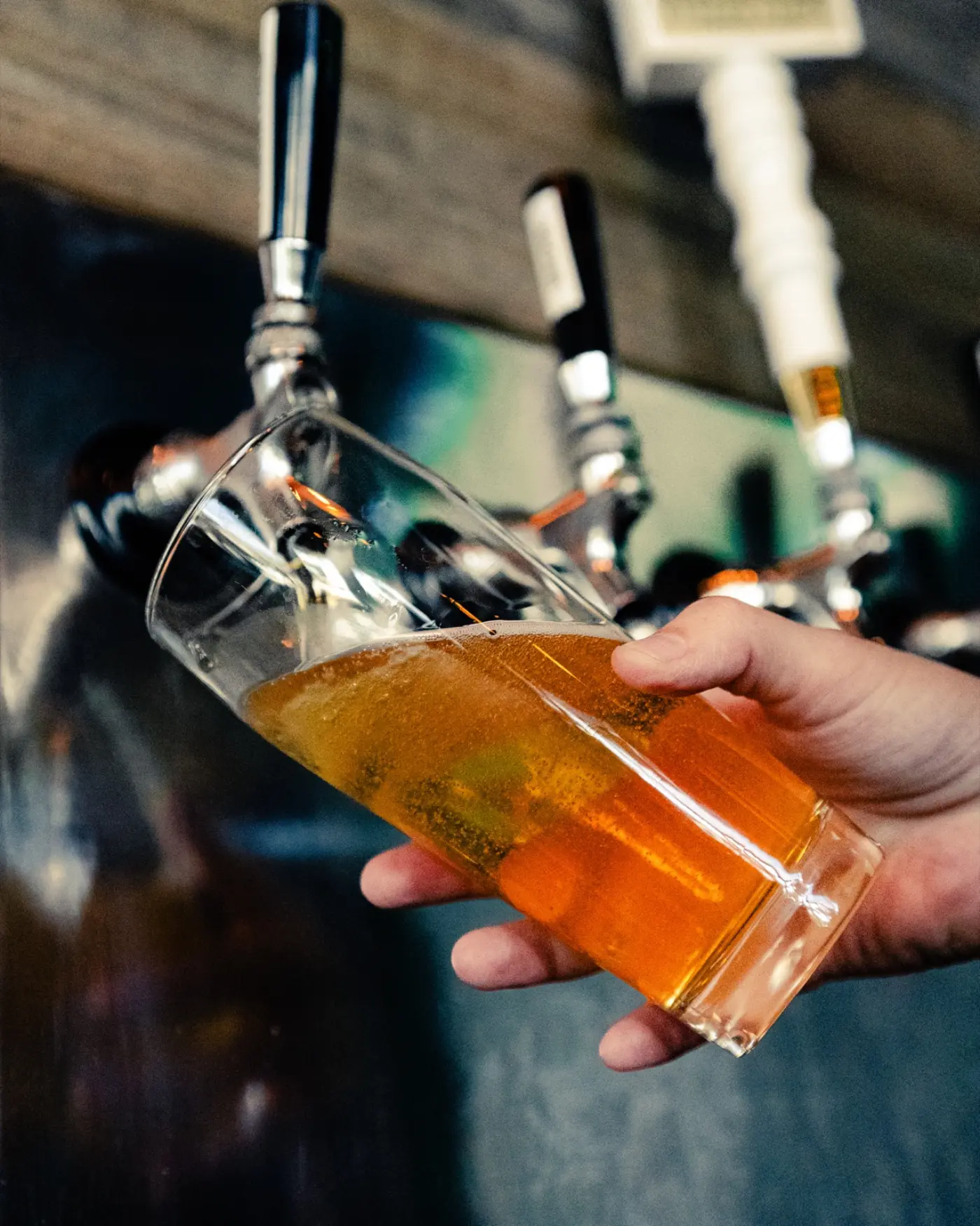 Bartender pulling a glass from a row of chrome taps