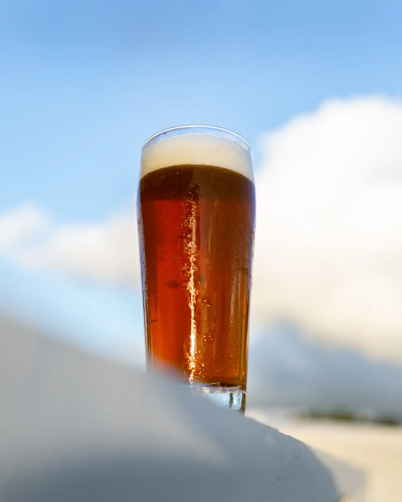 Pint of amber ale lit by sunlight against a blue Florida sky