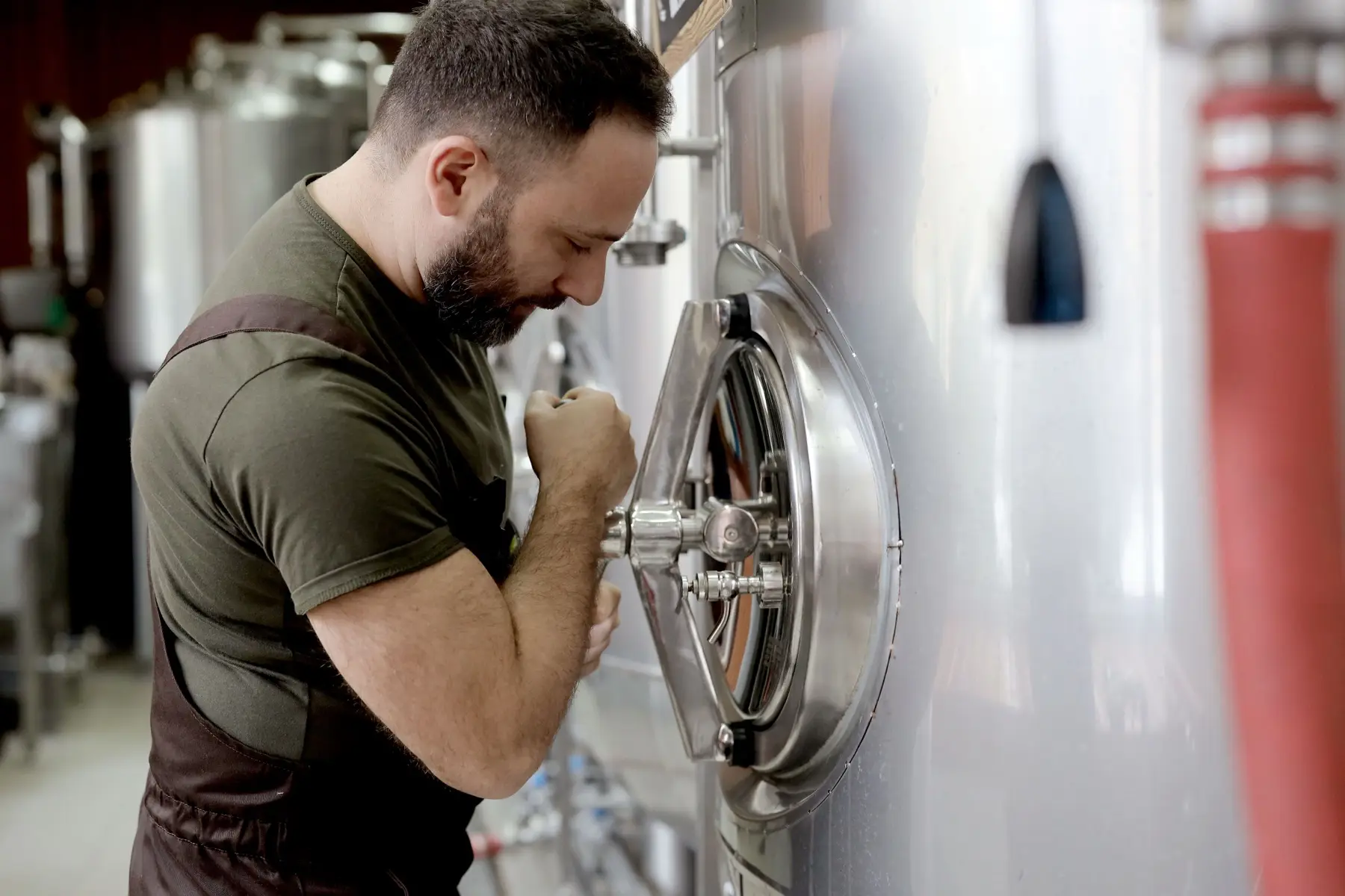 A brewer leaning into a fermentation tank at Celebration Brewing Co.